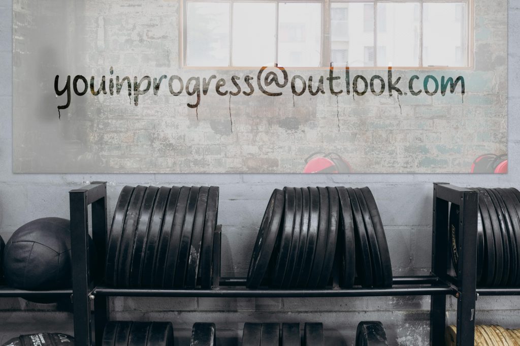 A gym mirror fogged with steam has the words youinprogress@outlook.com written in the condensation-representing a way to contact the site for support