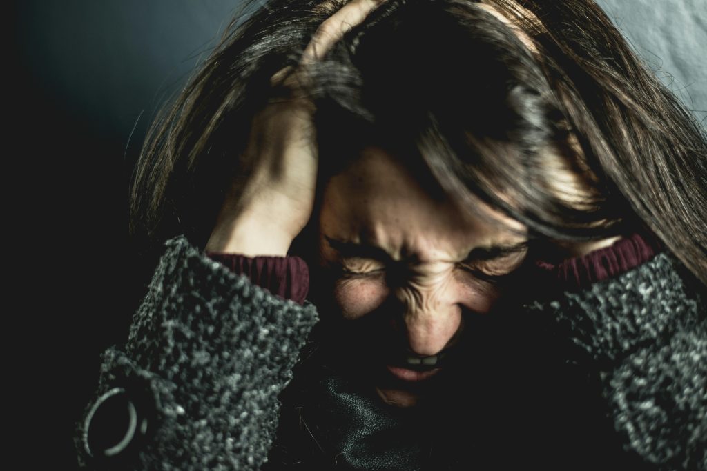A woman clutches her head in her hands as she searches for natural ways to stop anxiety attacks without medication